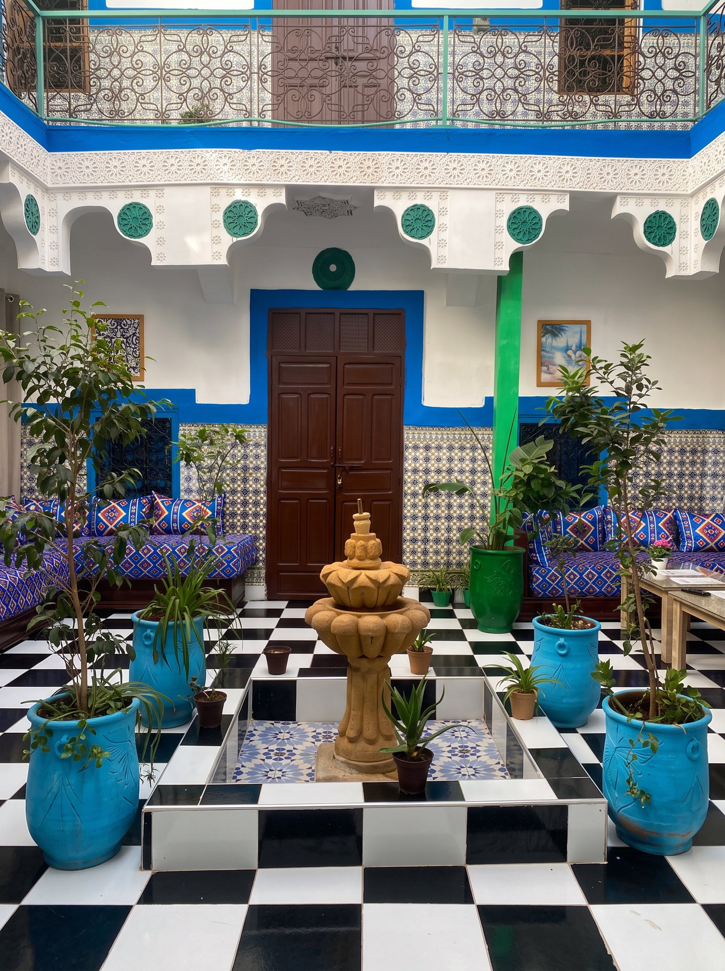 Patio central du Riad Dar Medina Land à la tombée du jour, arcades en cèdre sculpté, fontaine en zellige et lanternes en laiton allumées